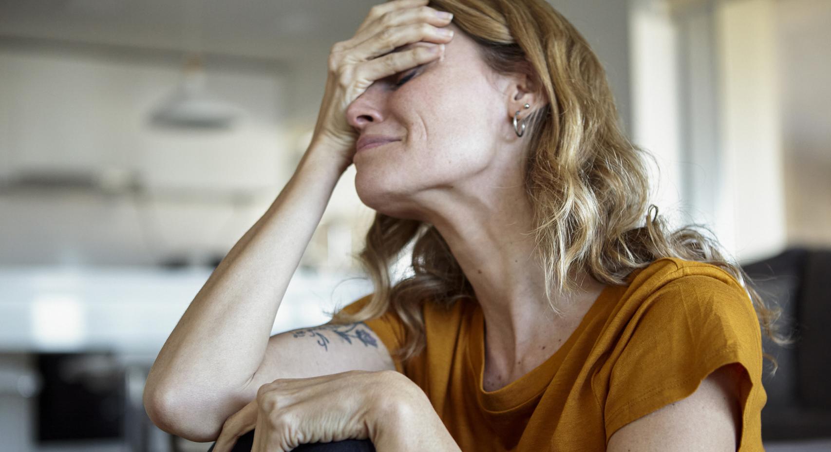 Mujer llorando tapando su rostro.