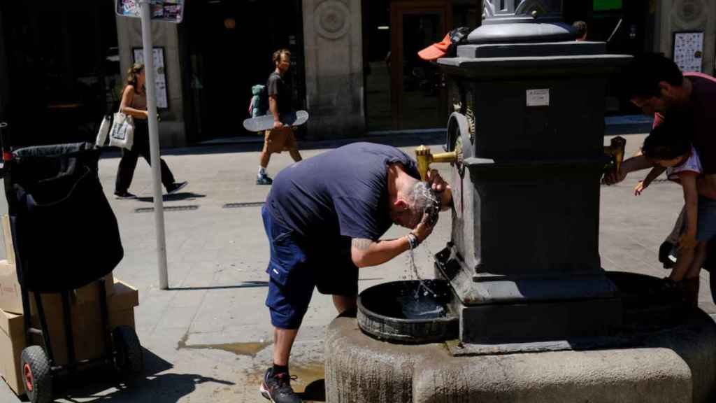Un hombre se refresca en Barcelona por el calor.