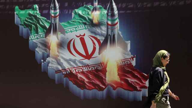 Una mujer iraní pasea frente a un cartel sobre misiles lanzados desde el país