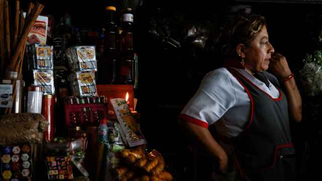 Una vendedora espera clientes en su puesto durante un corte de energía en Quito, Ecuador.