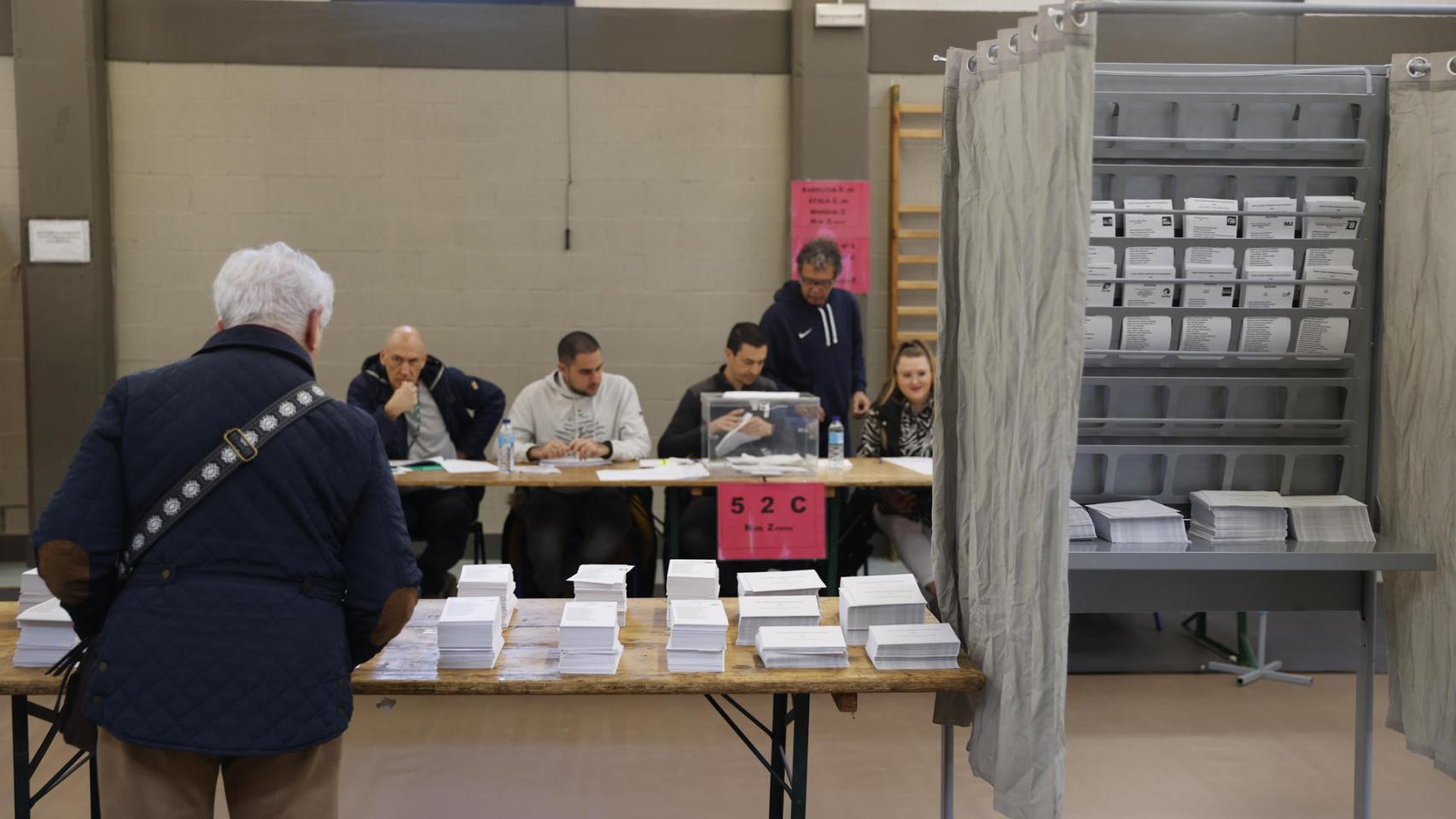 Elecciones en el País Vasco | Un hombre escoge papeleta para ejercer su derecho al voto en un colegio electoral en Durango, Vizcaya.