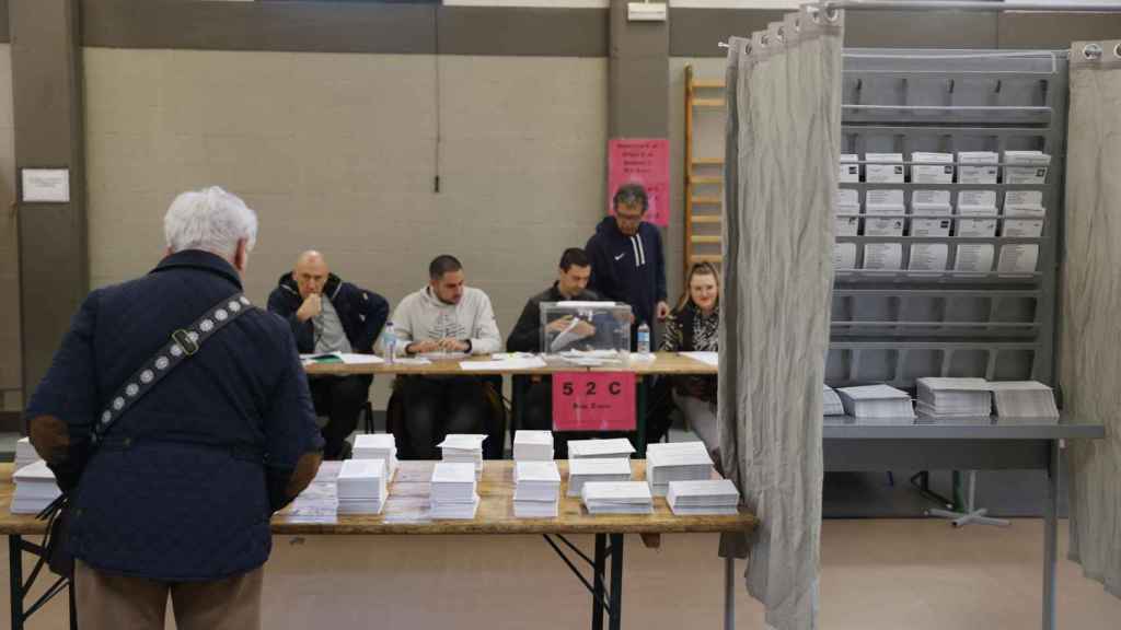 Un hombre escoge papeleta para ejercer su derecho al voto en un colegio electoral en Durango, Vizcaya.