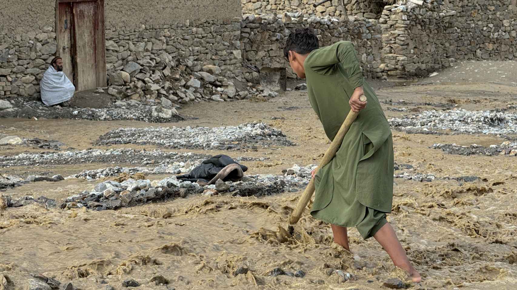 Un niño intenta arreglar los estragos de las inundaciones en Afganistán