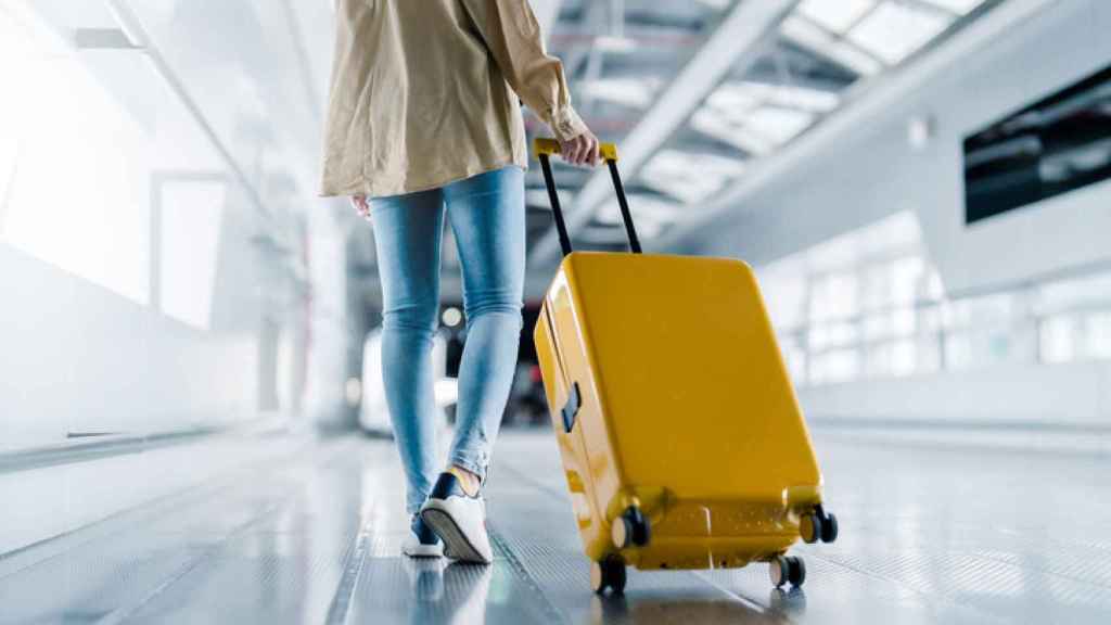Una mujer con equipaje y caminando por el aeropuerto.