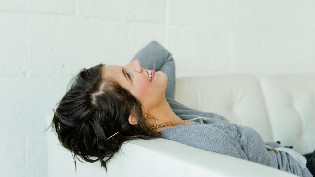 Mujer sonriente descansando en un sofá.