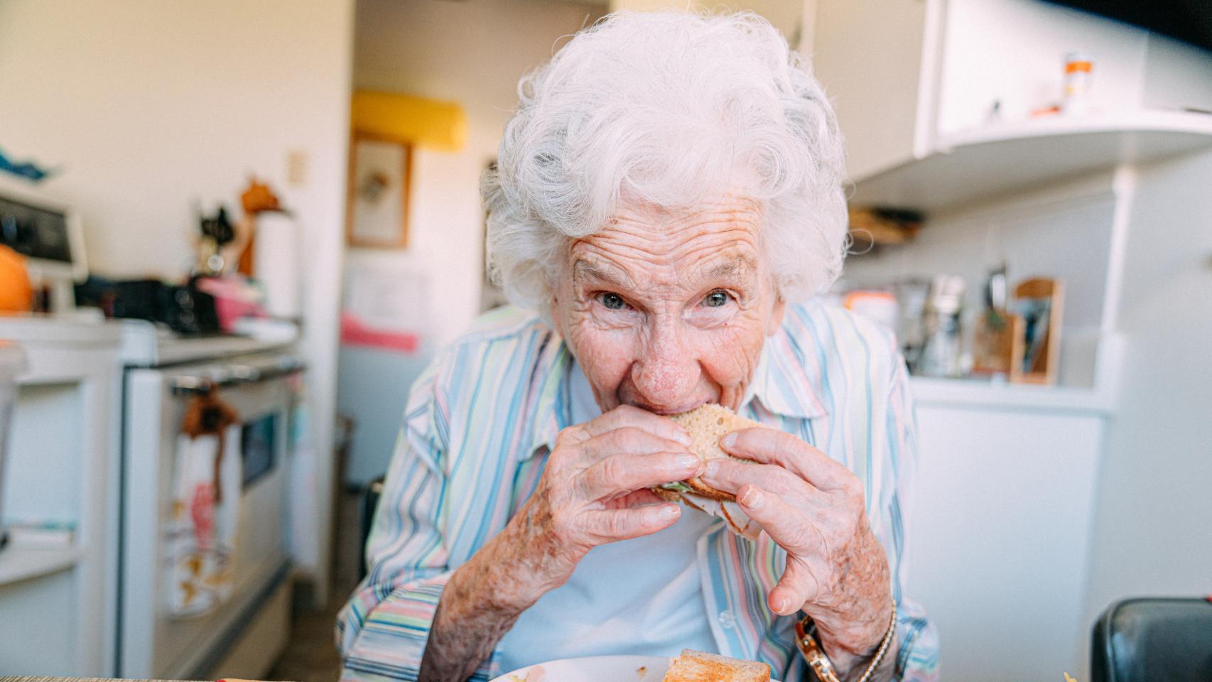 Mujer mordiendo un sándwich.