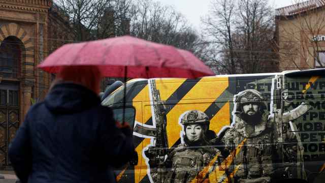 Una mujer camina frente a una furgoneta con un anuncio del servicio militar ucraniano en Kropivnitski.