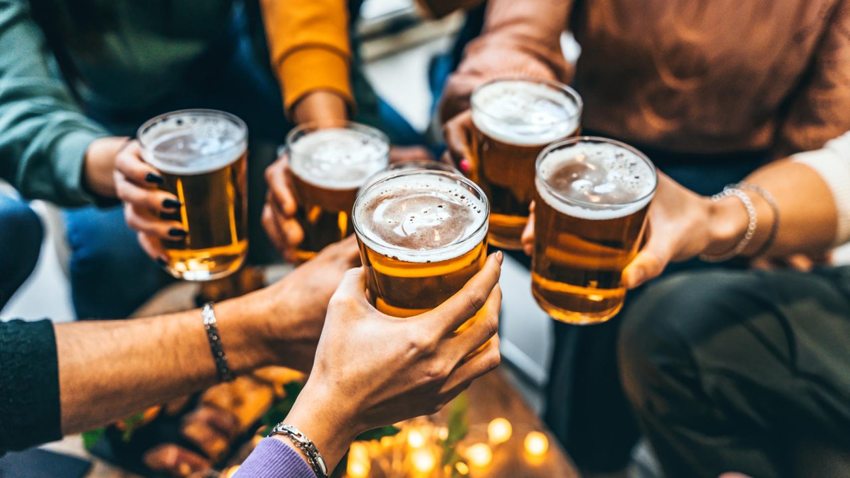 Varias personas brindando con vasos de cerveza.