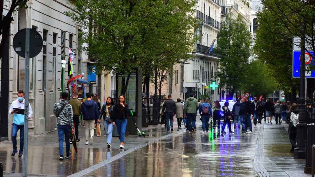 Los peatones se protegen de la lluvia.