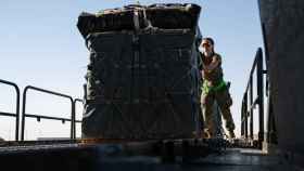 Una militar estadounidense carga ayuda humanitaria en un avión de transporte.