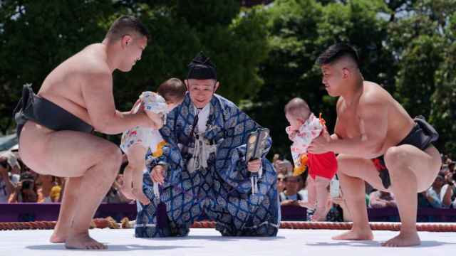 Luchadores de sumo sostienen a niños durante el concurso de bebés llorones de 'Naki Sumo'.