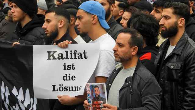 Un joven sostiene una pancarta que reza: El califato es la solución.
