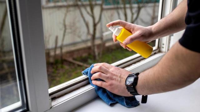 Una persona limpiando los rieles de una ventana.