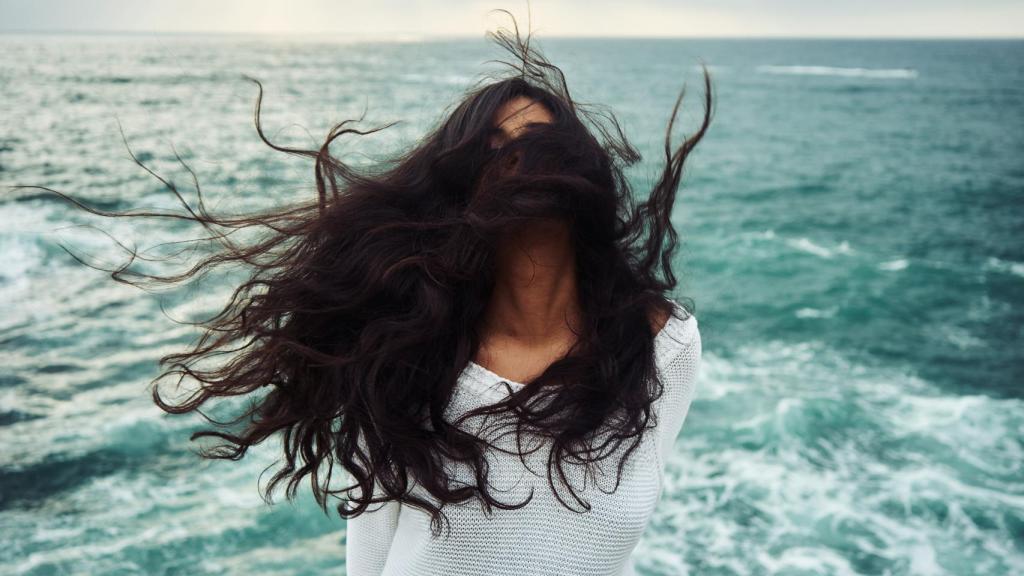 Mujer en el mar con el pelo al viento.