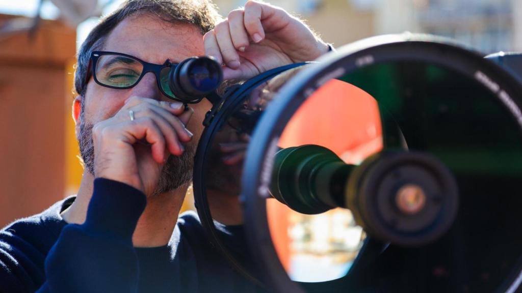 Javier Peralta mirando por un telescopio.