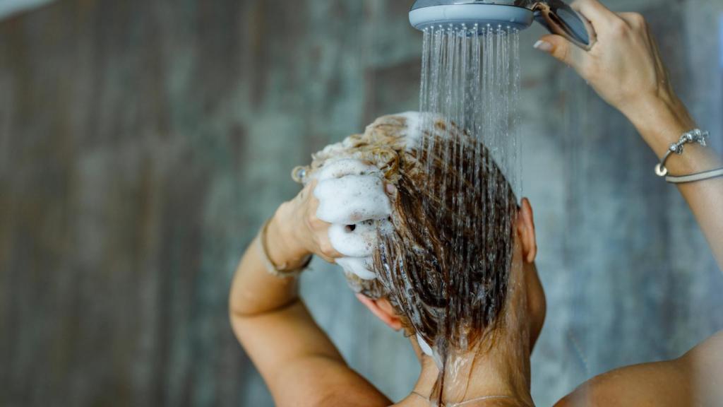 Mujer en la ducha lavándose el pelo.