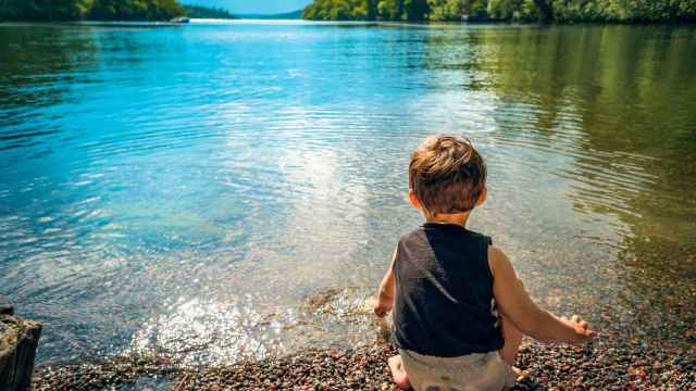 Un niño jugando al borde de un lago.