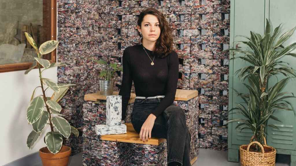 Clarisse Merlet, fundadora de FabBRICK, sobre una silla hecha de ropa usada.