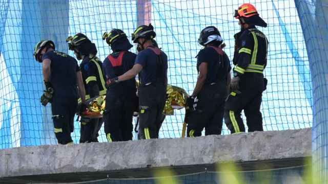 Un grupo de Bomberos mueve un cuerpo sin vida en un edificio donde se han derrumbado dos forjados este martes en Madrid.