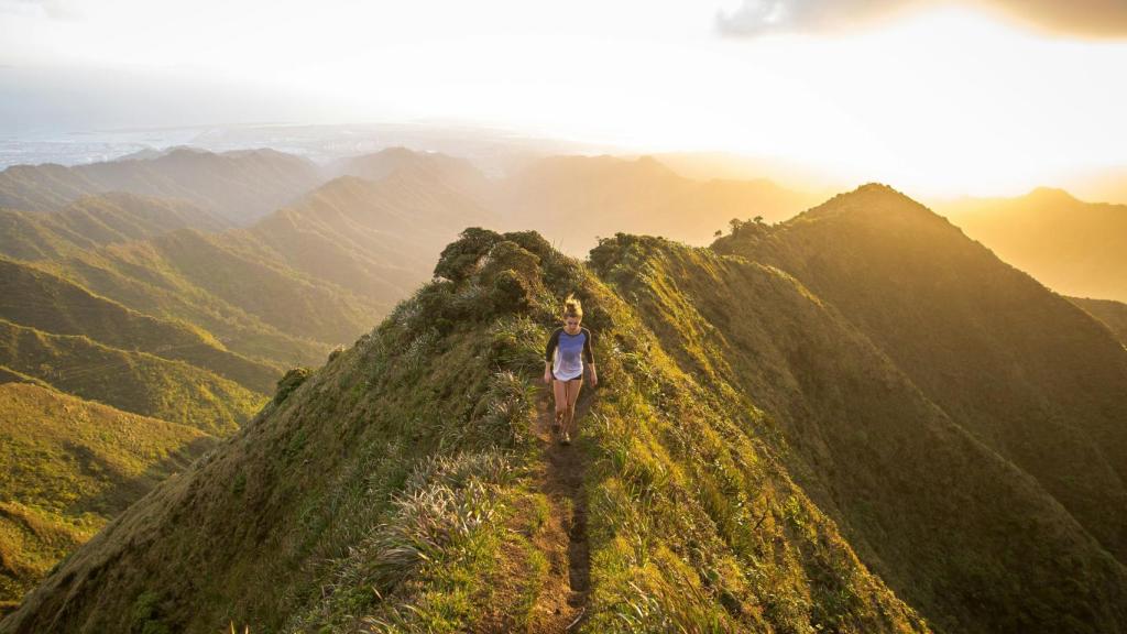 Mujer caminando por la cima de una montaña.