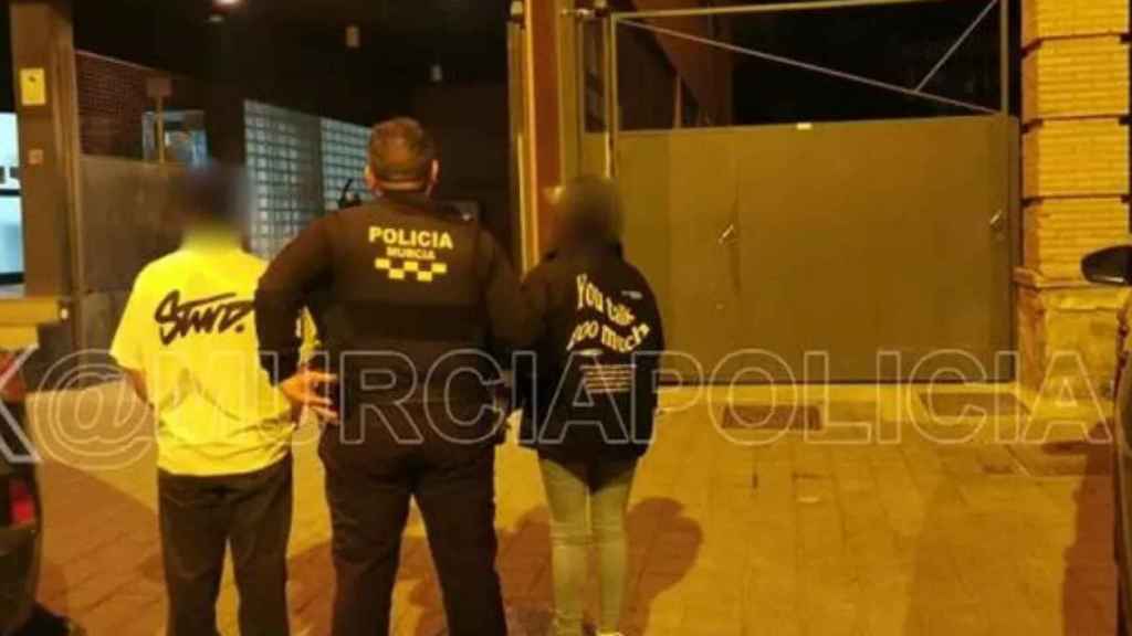 Un agente de la Policía Local de Murcia con los padres del niño cuando fueron puestos a disposición de la Policía Nacional, durante madrugada de este domingo,