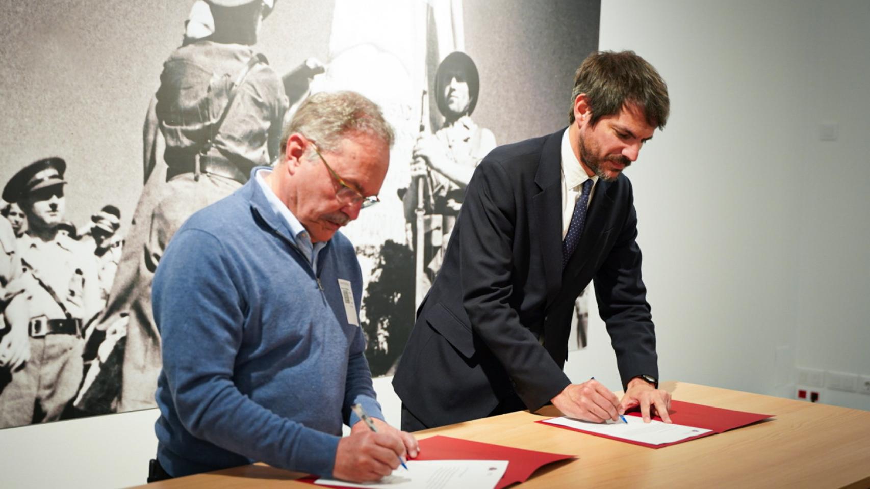 El ministro de Cultura, Ernest Urtasun (d), y Carlos Domínguez, directivo de la Asociación de Amigos de las Brigadas Internacionales (i), firman el depósito de sus fondos en el Archivo Histórico de Movimientos Sociales. Foto: Ministerio de Cultura