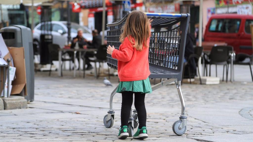 Una niña camina junto a la terraza de un bar en el centro de Madrid.