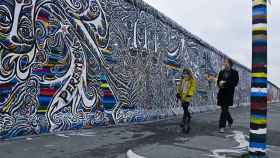 Personas caminando junto al Muro de Berlín