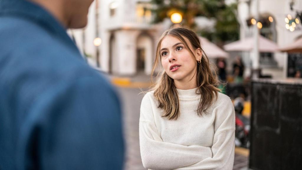 Mujer con brazos cruzados mirando a un hombre.