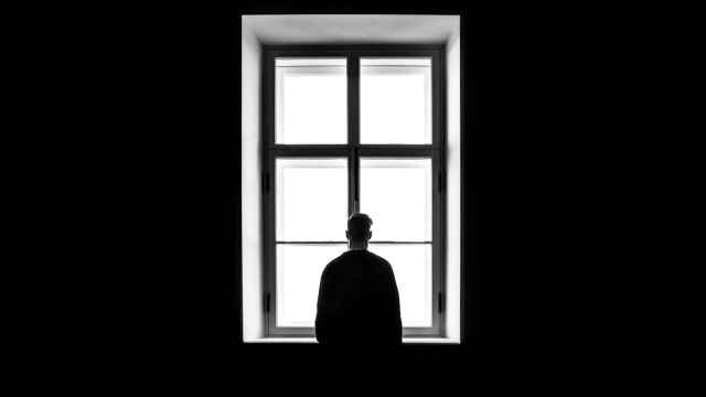 Una imagen de archivo de un joven mirando solo por la ventana.