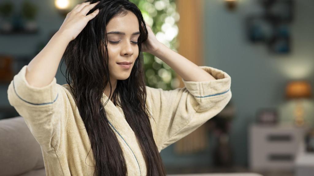 Mujer con el pelo húmedo masajeándoselo.