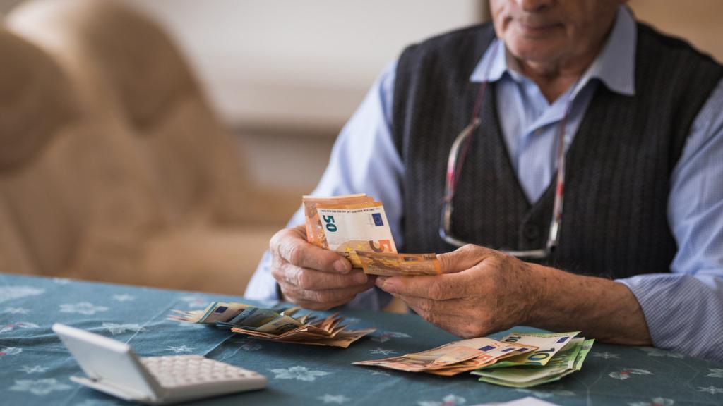 Imagen de archivo de un jubilado echando cuentas con dinero.