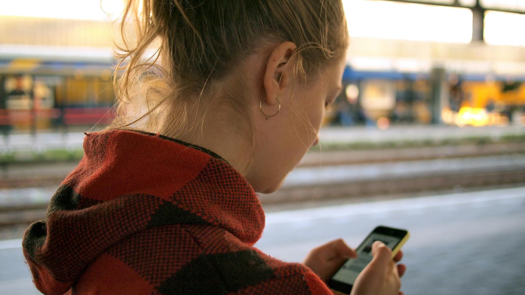 Una joven sosteniendo un teléfono móvil.