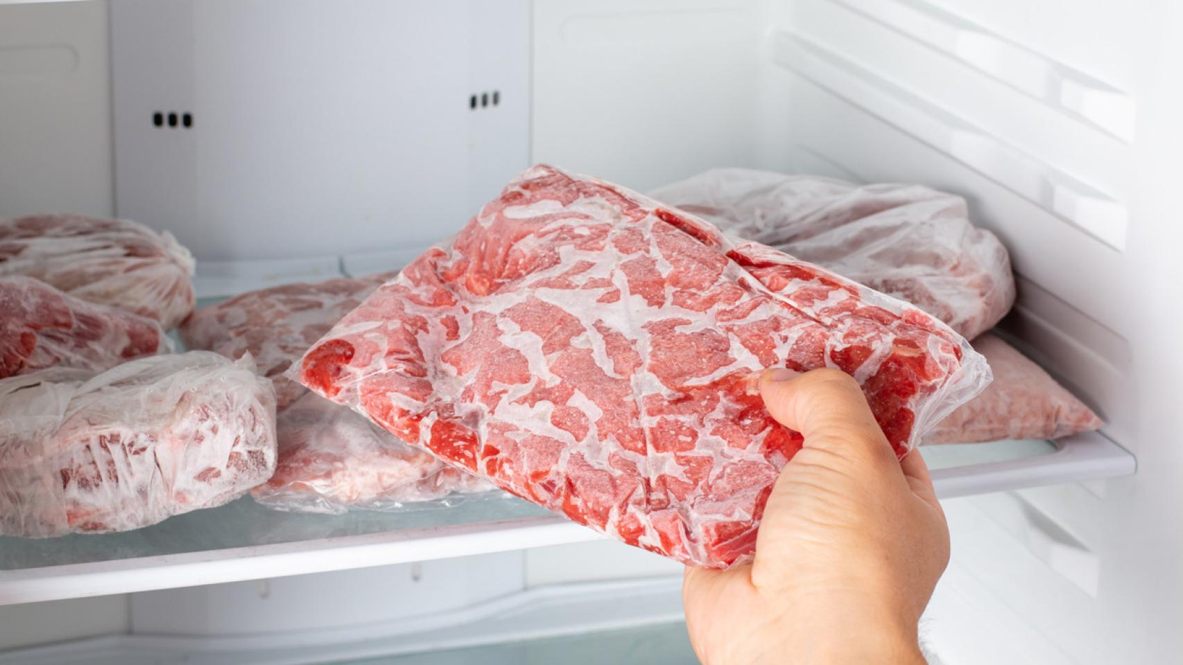 Un hombre sacando carne congelada del congelador.