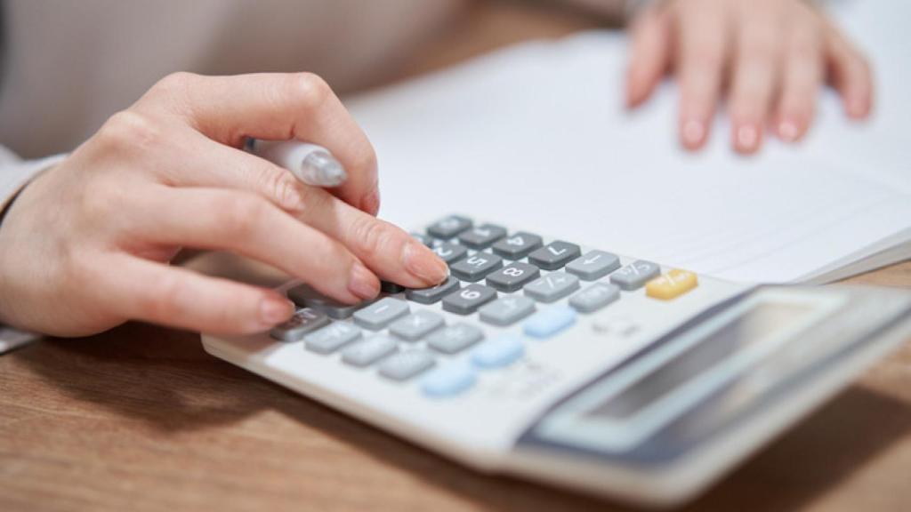 Mujer haciendo cálculos con calculadora.