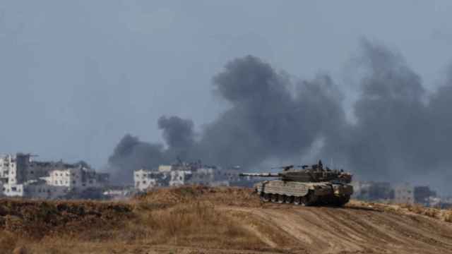Un tanque israelí mantiene su posición mientras se levanta humo en Gaza.