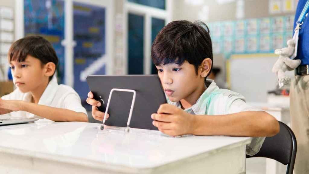 Dos escolares con dispositivos electrónicos.