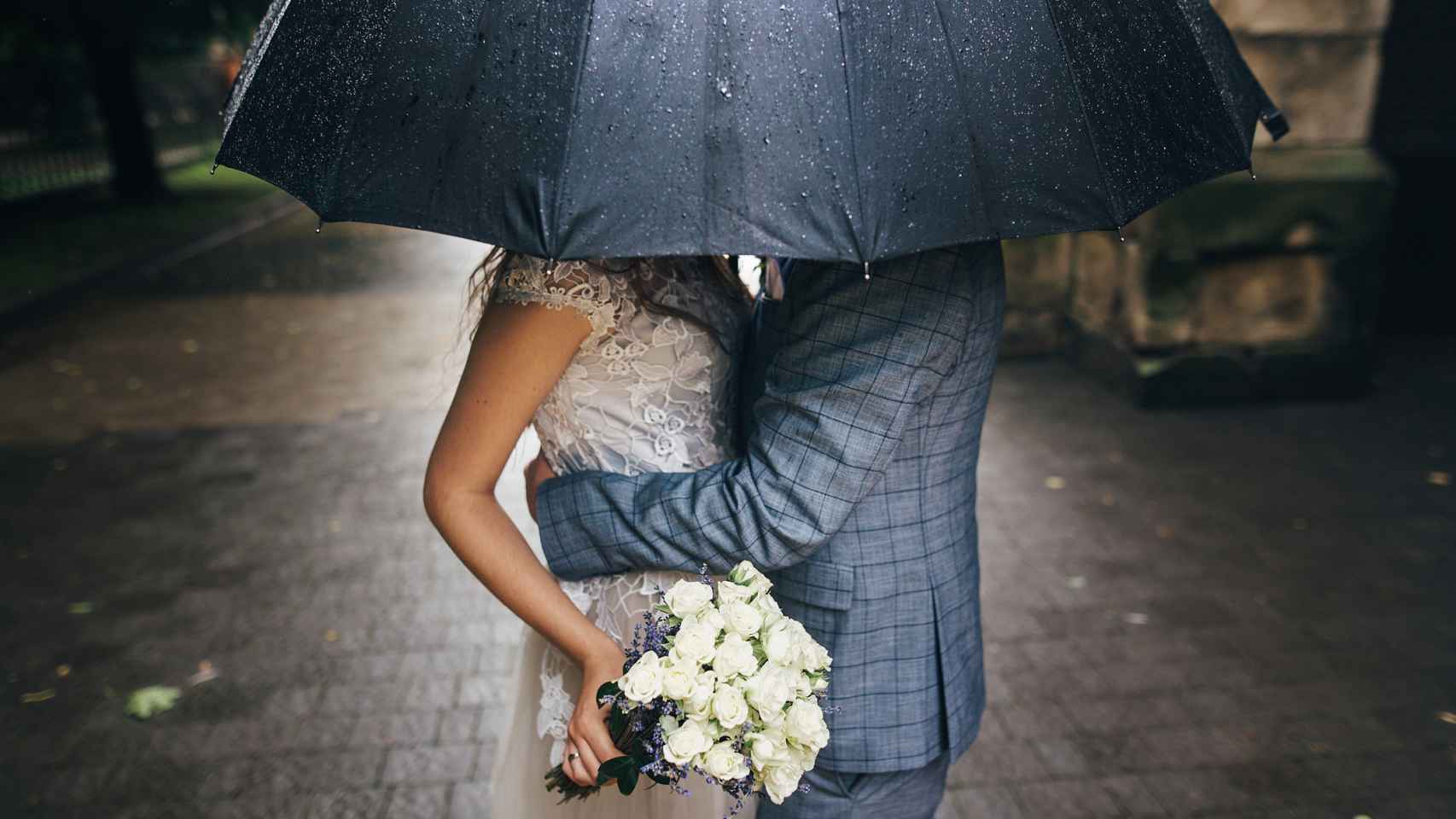 Novios bajo un paraguas el día de la boda.