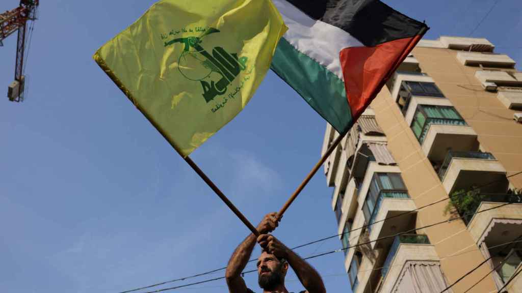 Un hombre levanta una bandera de Palestina y a la vez una de Hezbollah.