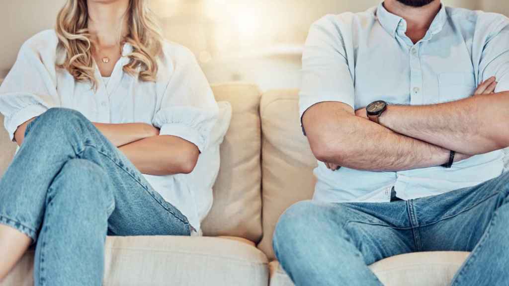 Pareja sentada en el sofá con los brazos cruzados.