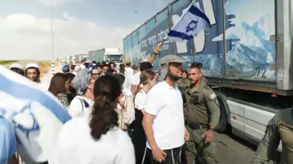 Manifestantes israelíes junto a camiones de ayuda destinados a Gaza.