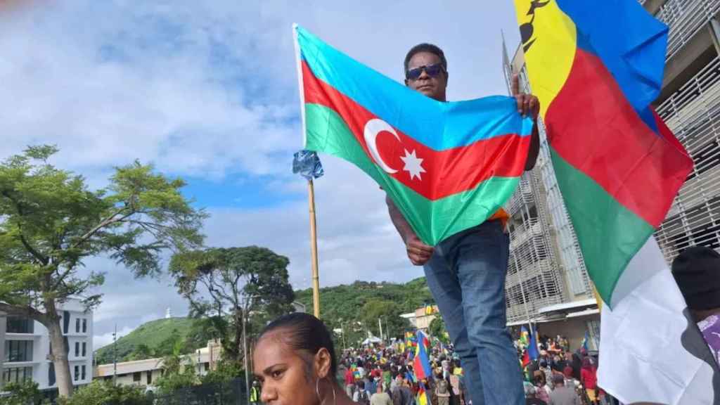 Un manifestante ondea la bandera azerbaiyana junto a una bandera canaca, el 16 de mayo en Numea.