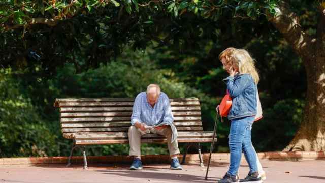 Varios jubilados caminando y descansando en un parque.
