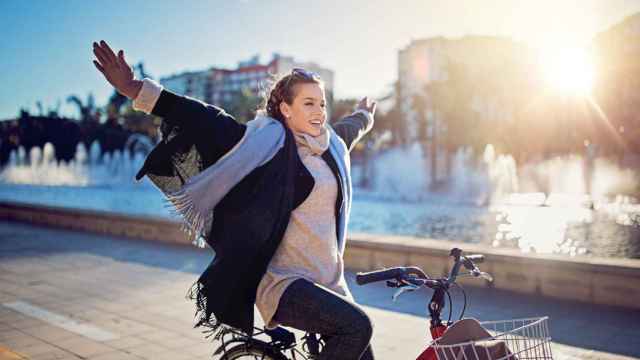 Mujer montando en bicicleta con los brazos en alto.
