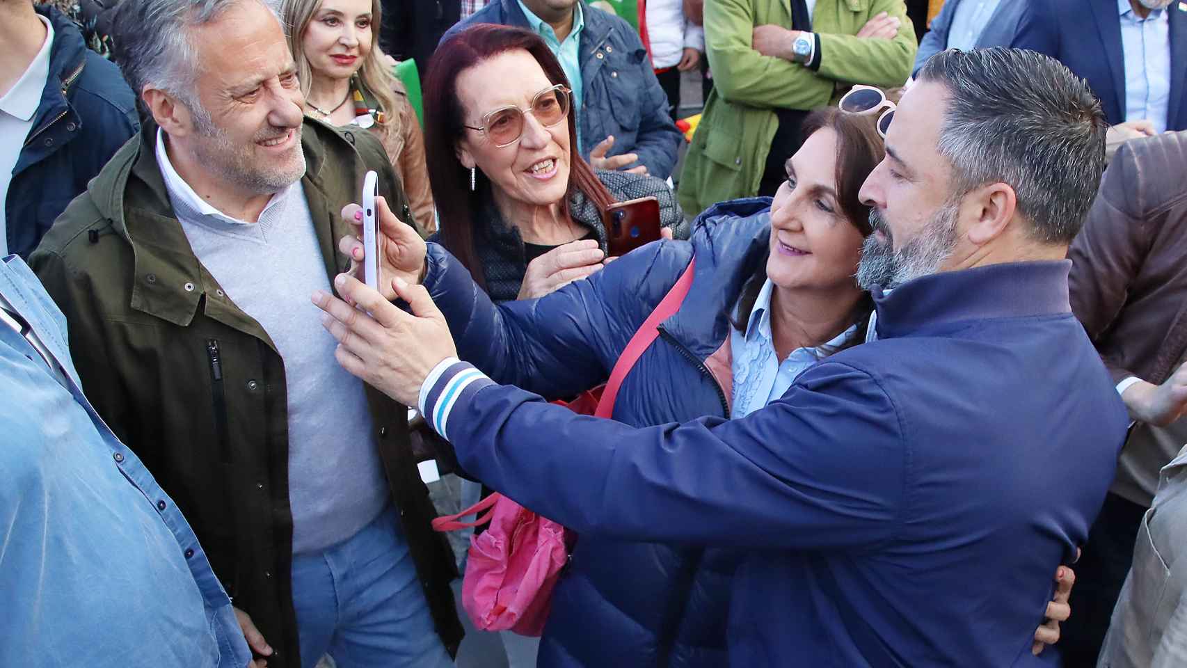 Santiago Abascal se hace una fotografía con una simpatizante de Vox ante la mirada de Carlos Pollán