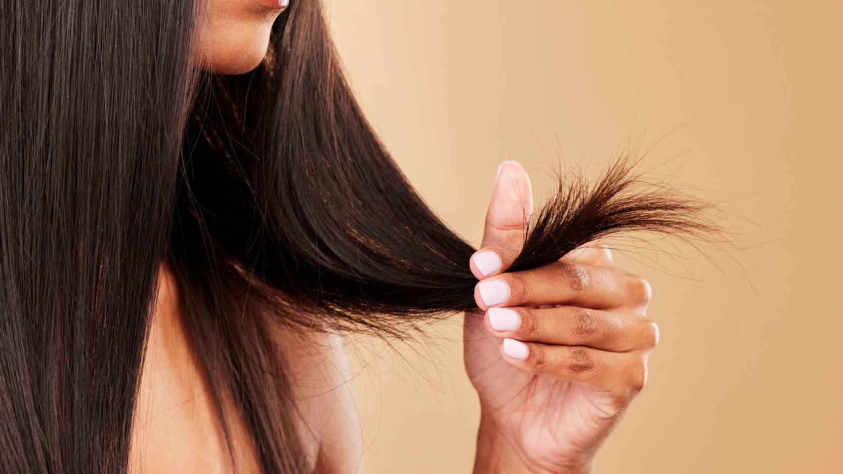 Mujer tocándose las puntas del pelo.