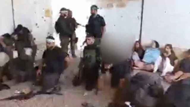 Milicianos de Hamás y, en el fondo de la imagen, las cinco jóvenes israelíes secuestradas el 7 de octubre de 2023.