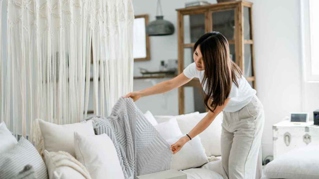 Mujer ordenando una manta de su sofá.