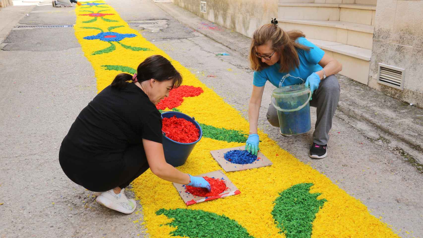 Dos vecinas decorando las alfombras de flores.