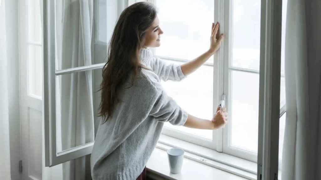 Imagen de archivo de una mujer abriendo la ventana.